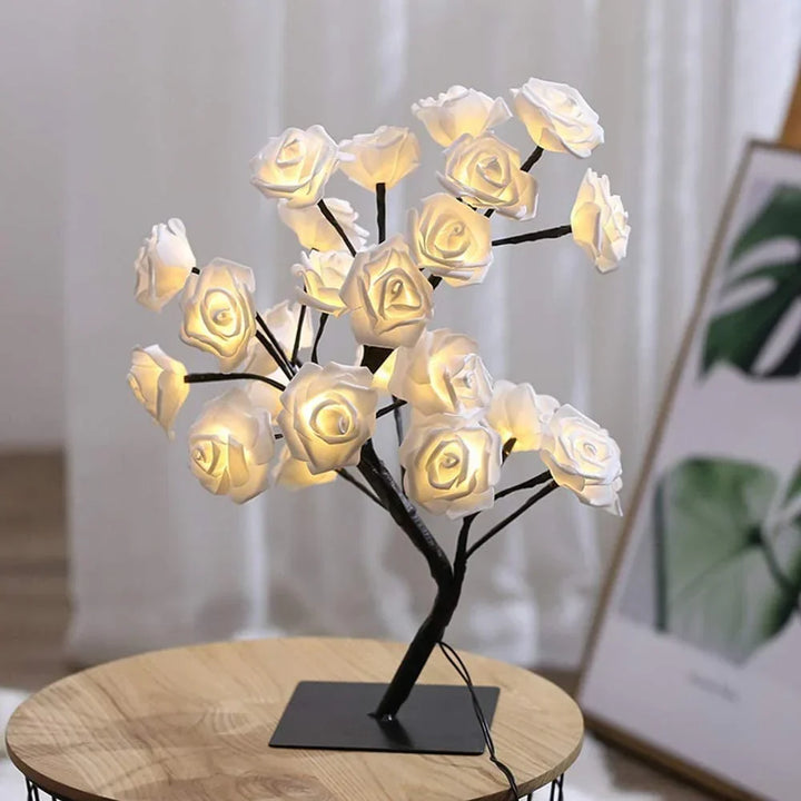 Close-up of glowing warm white LED rose blossoms on a decorative bonsai tree lamp.