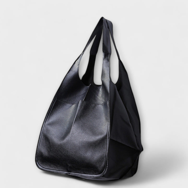 Close-up of women's oversized brown leather weekender travel bag, showing texture & quality.