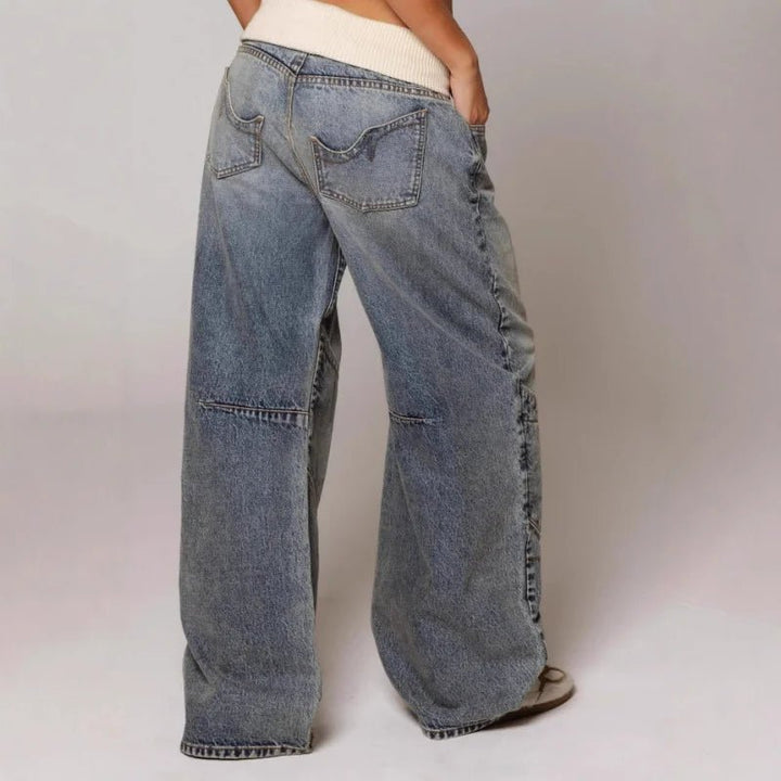 Textured image of women's vintage light wash denim. Features detailed patchwork and a relaxed wide leg fit.
