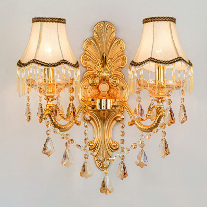 Close-up of the ornate metal base of a Victorian wall lamp, highlighting gold finish & traditional craftsmanship.