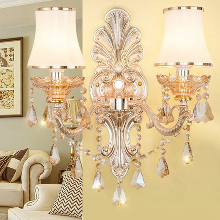 Beautiful gold Victorian wall lamp casting warm ambient light, adorned with a decorative shade & crystals.