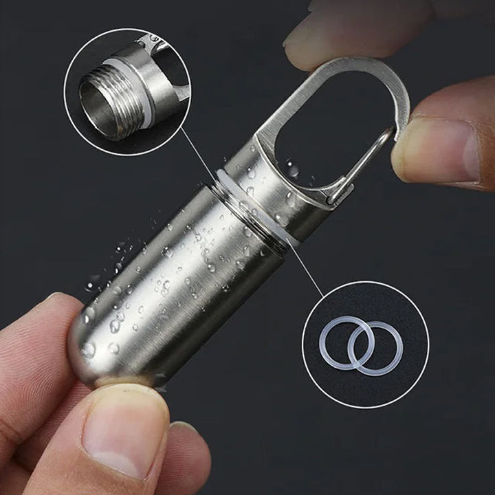 Stainless steel waterproof pill box for daily medication, portable keychain organizer.