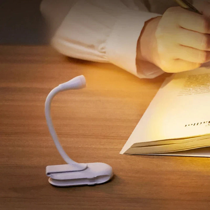 Reading a book comfortably with a clip-on LED light, dimmable for eye protection, portable design.