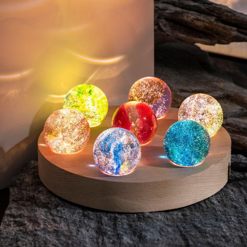 Modern crystal galaxy orb lamp with a radiant wooden LED base, providing soft ambient lighting.