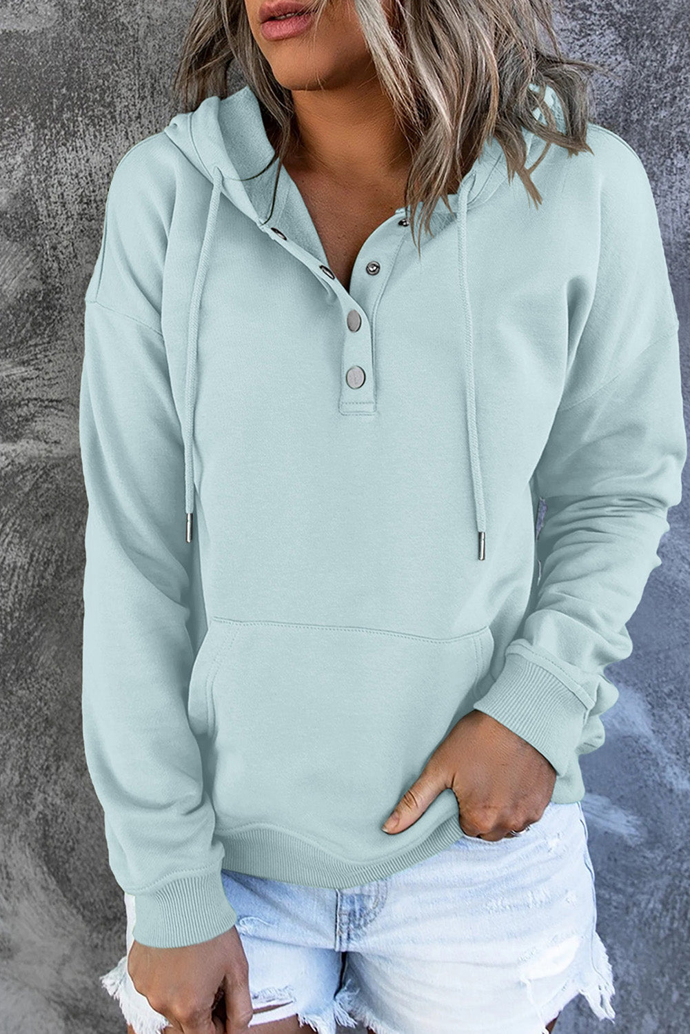 Side profile of a woman wearing a cozy hooded sweater. Everyday casual comfort.