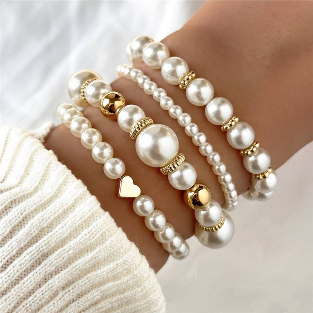 Fashionable women's 4-piece faux pearl heart beaded bracelet set. White layered jewelry with elegant design.