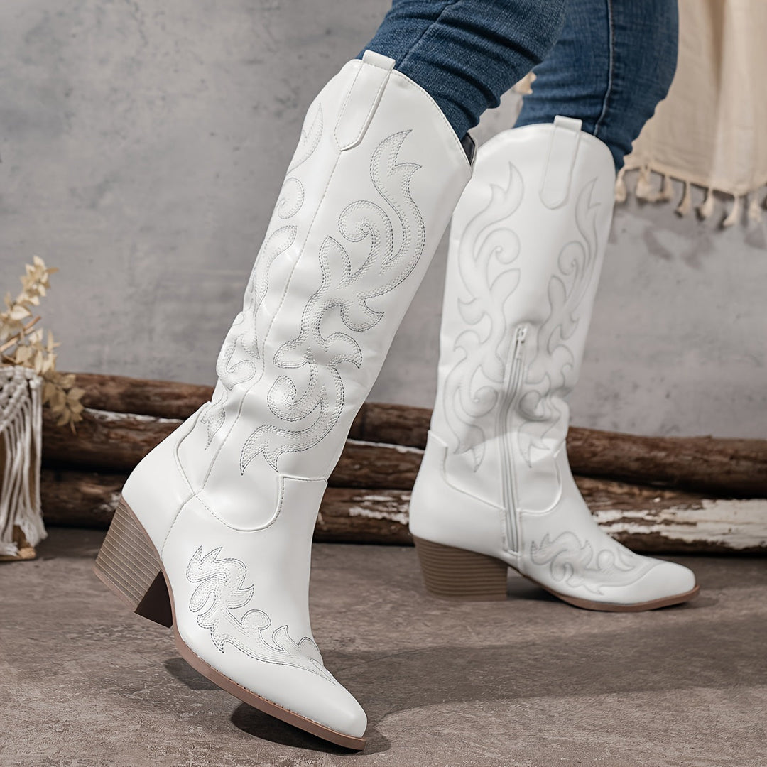 White women's cowboy boots, knee high with intricate western patterns, ideal for a stylish statement.