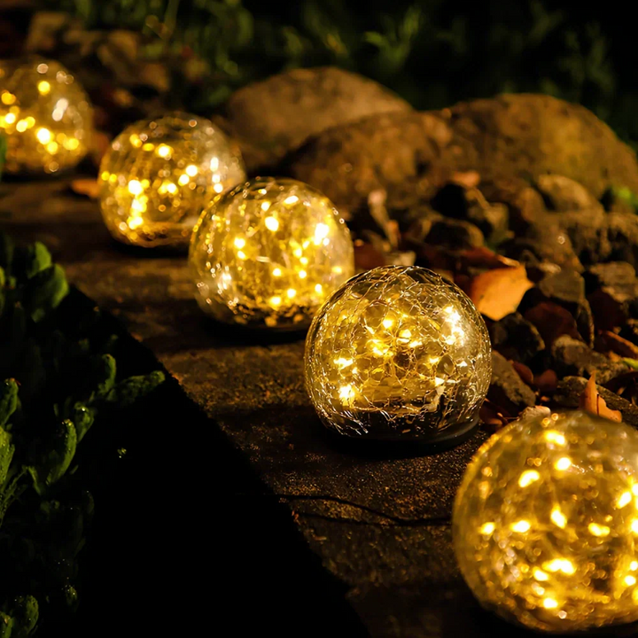 Warm white glow from a crackled glass solar orb, perfect LED garden light.
