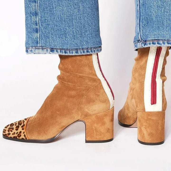 Close-up of women's ankle boots showcasing the distinctive leopard print toe and sturdy block heel.