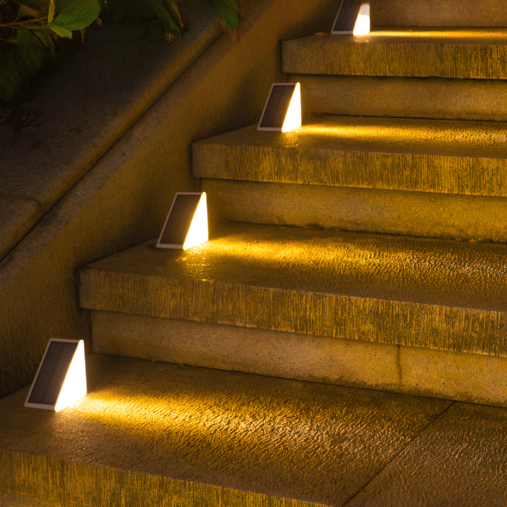 Weatherproof solar deck lights installed on wooden railing, providing warm pathway illumination for evening.