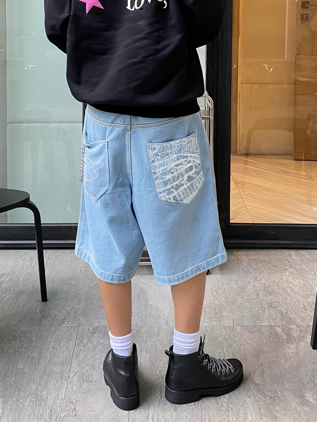 Fashionable men's knee-length denim shorts with unique floral embroidery, a summer essential.