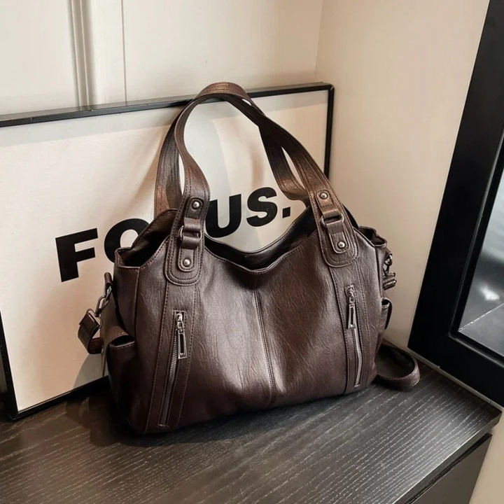 Elegant women's faux leather duffle bag with adjustable shoulder strap, perfect for work or travel.