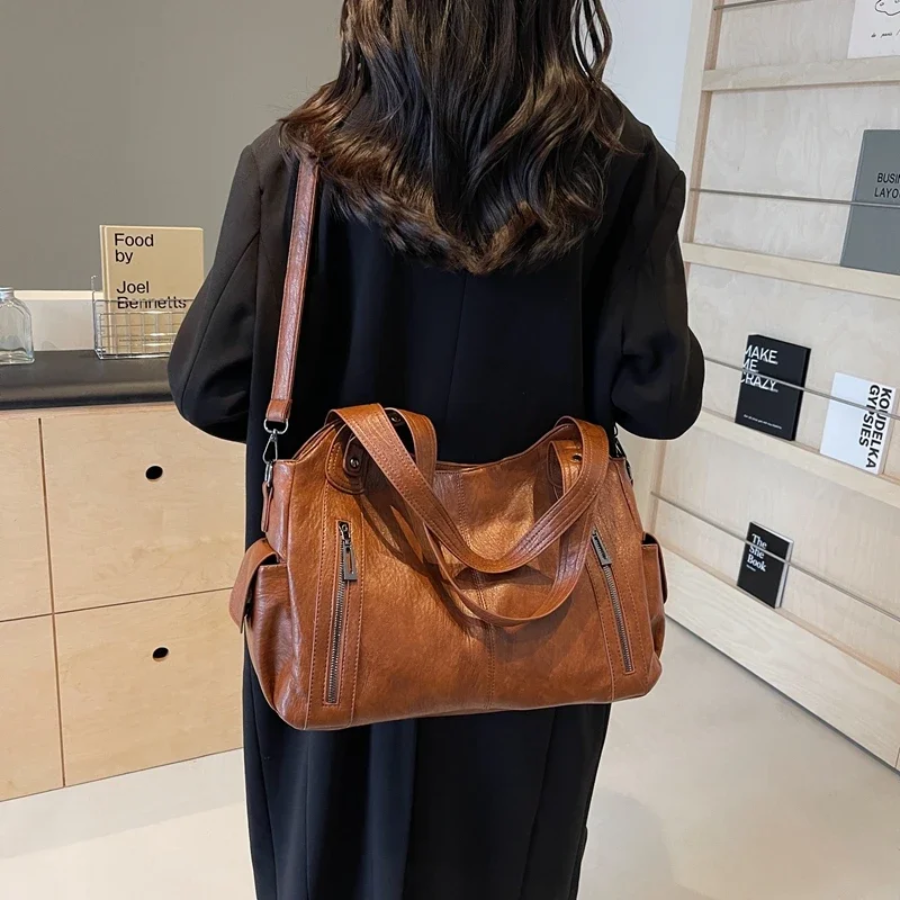 Modern women's faux leather duffle bag with comfortable shoulder strap, ideal for work, travel, & daily errands.