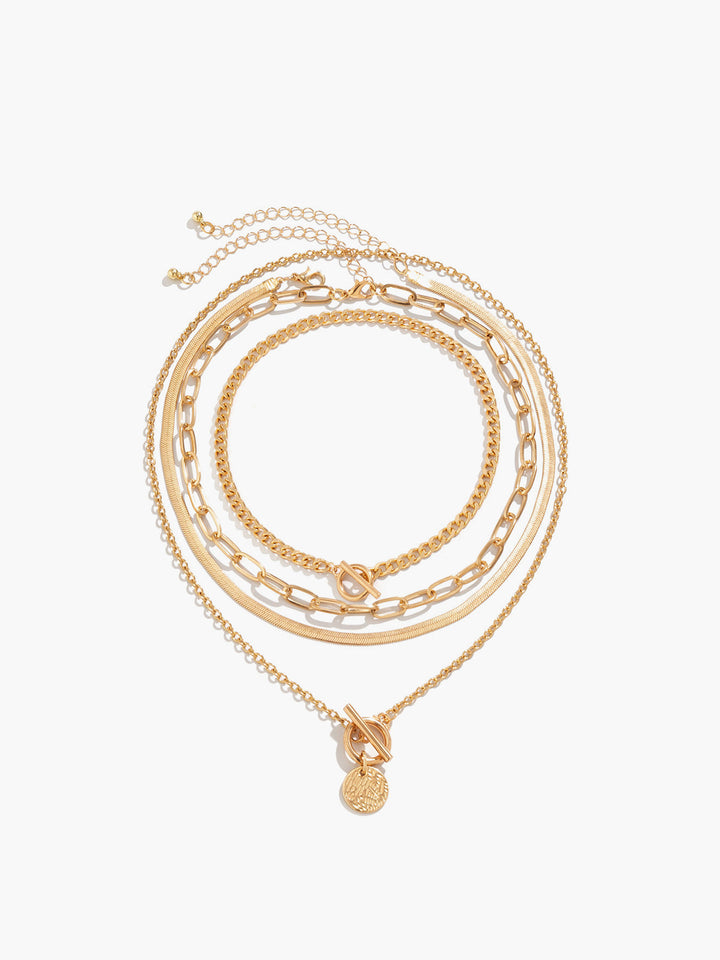 Close-up of a women's gold layered pendant necklace featuring multiple delicate chains & a detailed coin charm.