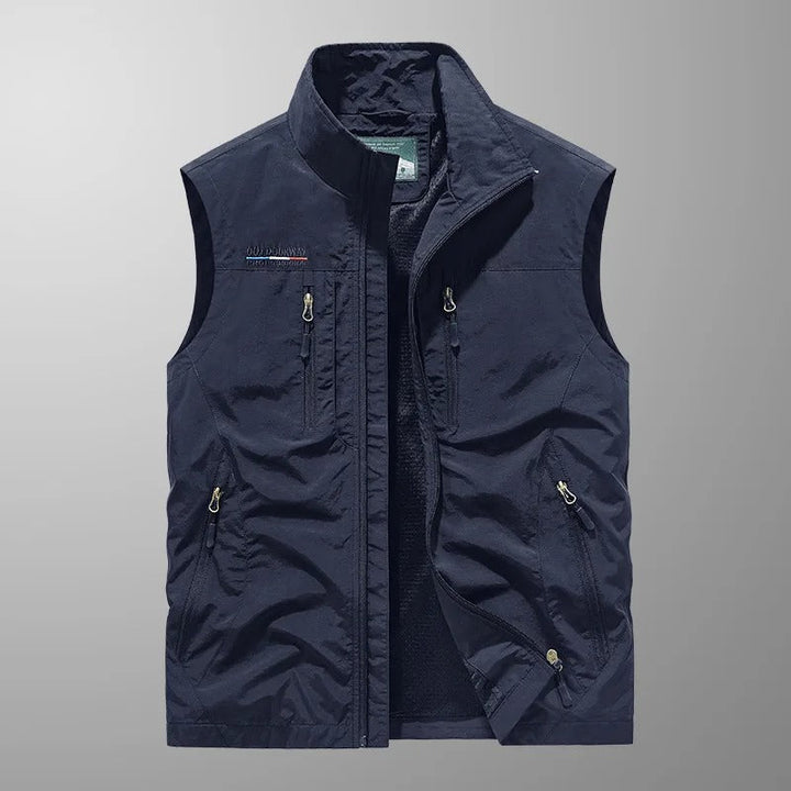 Man wearing a lightweight sleeveless cargo vest, perfect for outdoor hiking & travel, with functional zip pockets.