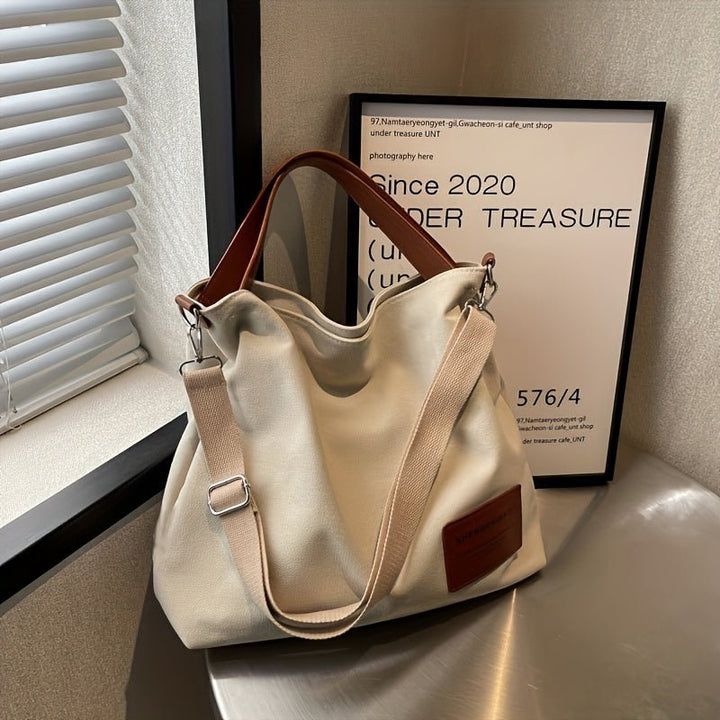 Spacious cream white canvas shoulder tote bag for women with an adjustable strap, ideal for work or travel.