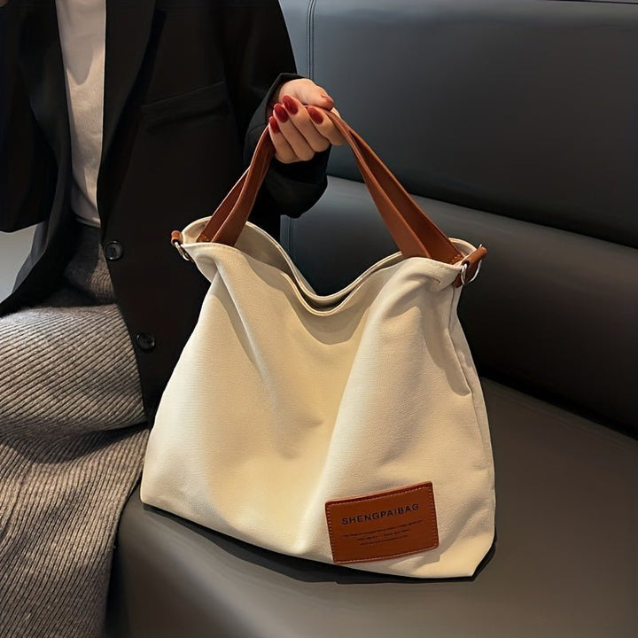Stylish black canvas hobo tote bag for women, large capacity with adjustable shoulder strap, great for travel.