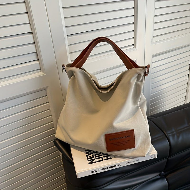 Elegant black canvas shoulder tote bag for women, featuring a large design and comfortable adjustable strap.
