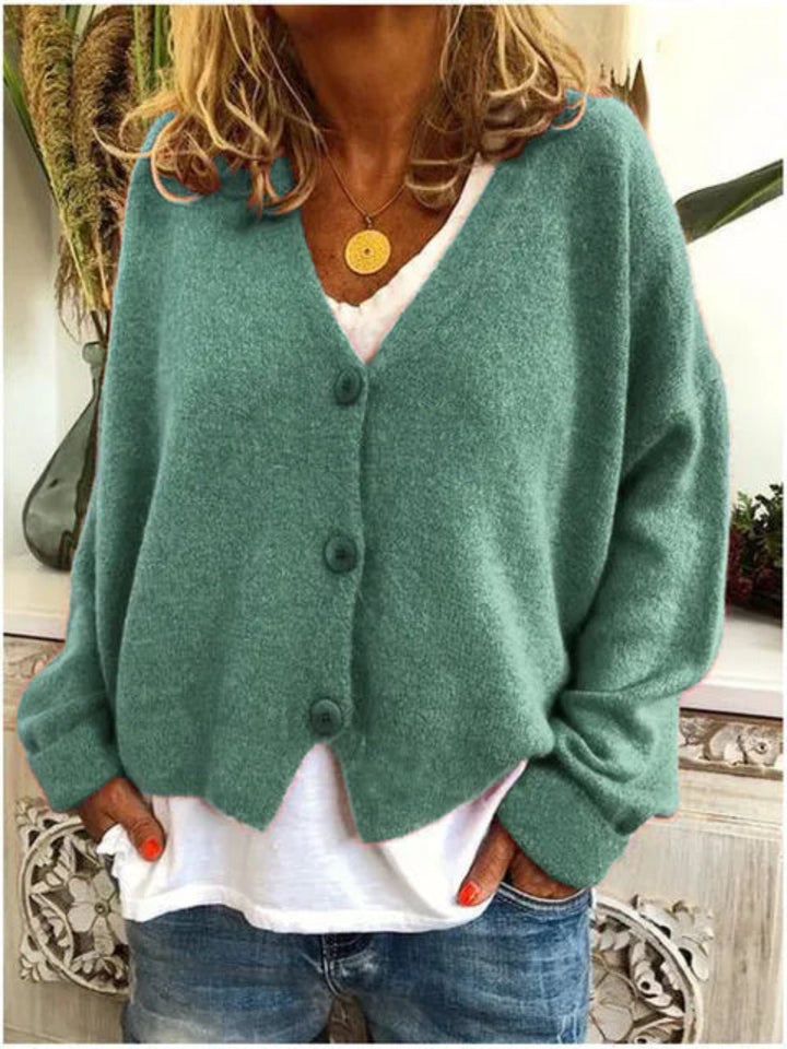 Women's fashion V-neck button-front knit cardigan on a hanger, showcasing its relaxed fit & versatile design.
