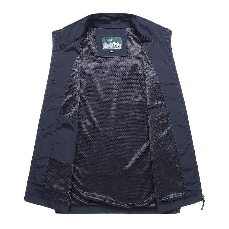 Man wearing a dark water-resistant utility vest with zip pockets, suitable for active outdoor use or casual daily wear.