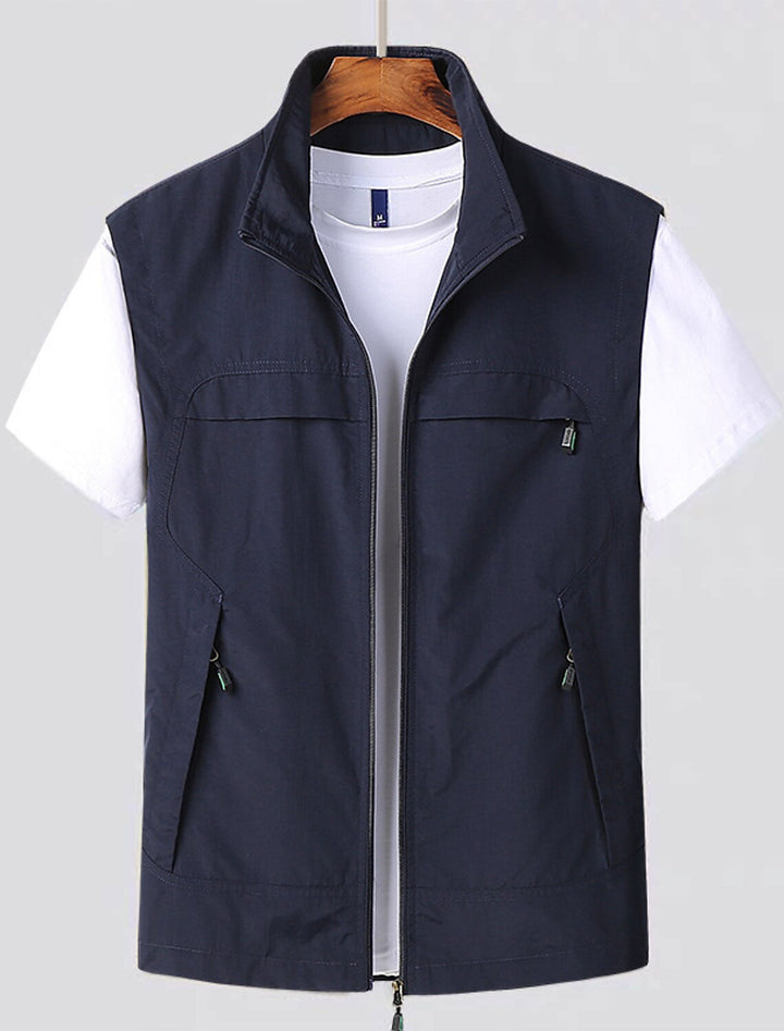 Men's water-resistant utility vest with stand collar, front zip closure, and multiple zip pockets for outdoor activities.