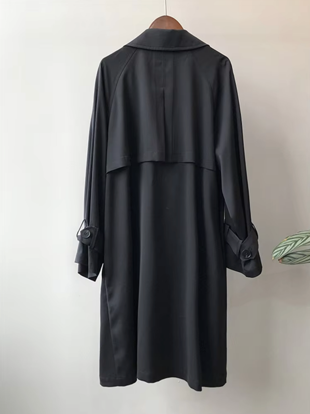 Close-up of the double-breasted front and belted waist on a women's waterproof long trench coat, classic elegant style.