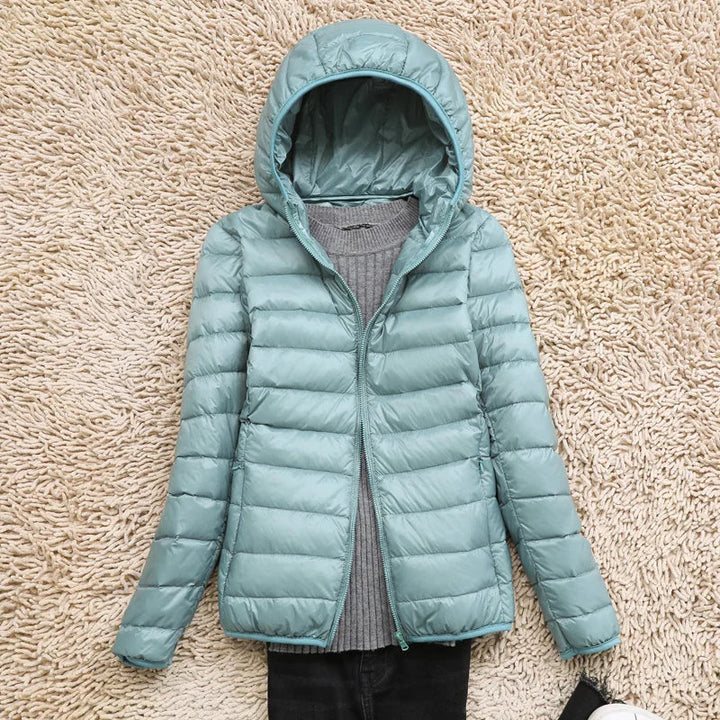 Woman packing a lightweight puffer jacket into its small pouch. Convenient travel outerwear.