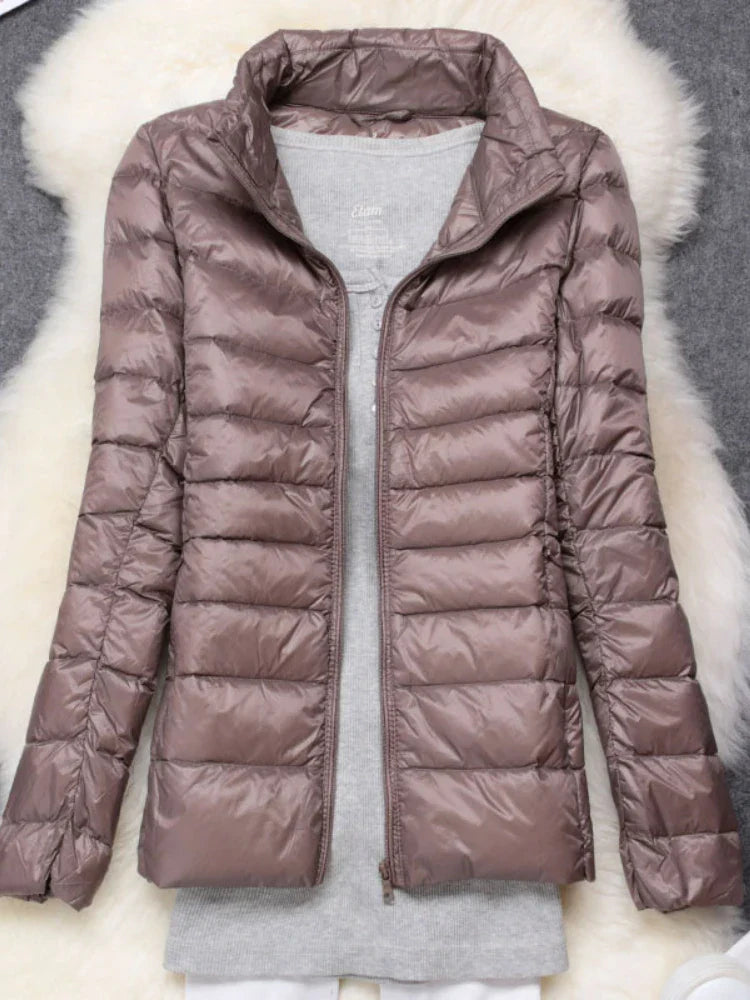 Woman enjoying a snowy landscape in her warm, hooded ultralight puffer jacket. Winter ready.