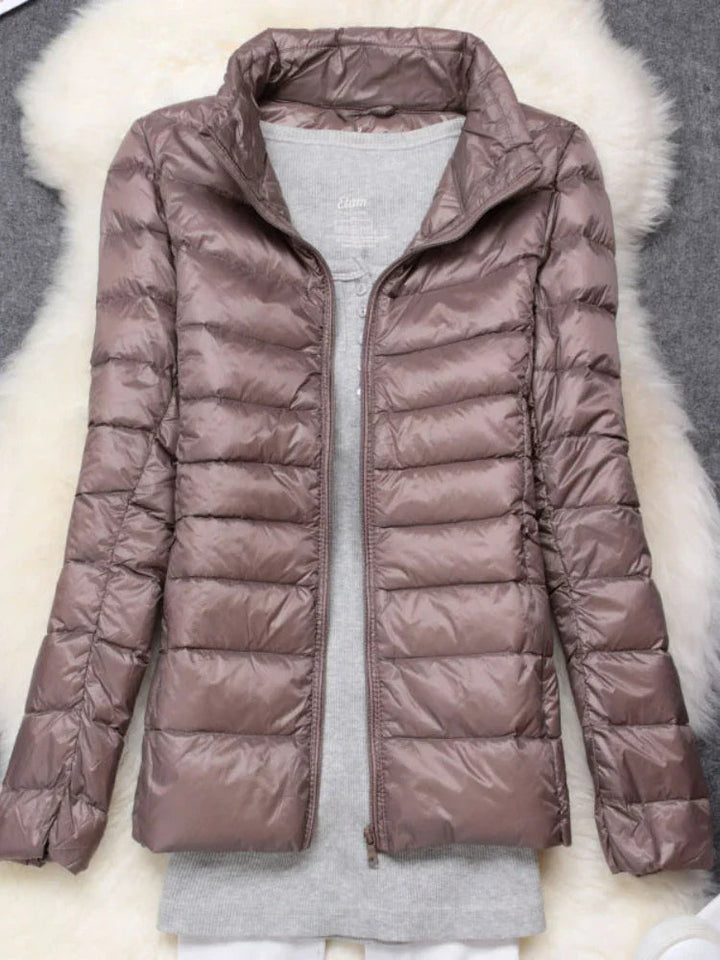 Woman enjoying a snowy landscape in her warm, hooded ultralight puffer jacket. Winter ready.