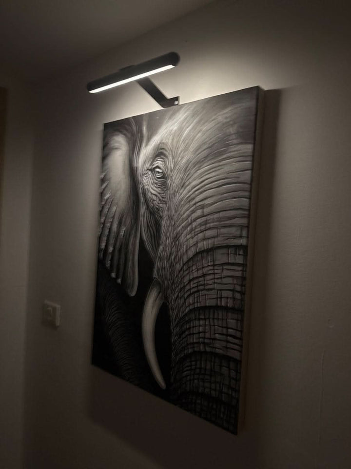 Rechargeable LED picture light for artwork. Dimmable wireless wall lamp illuminates art with modern sleek design.