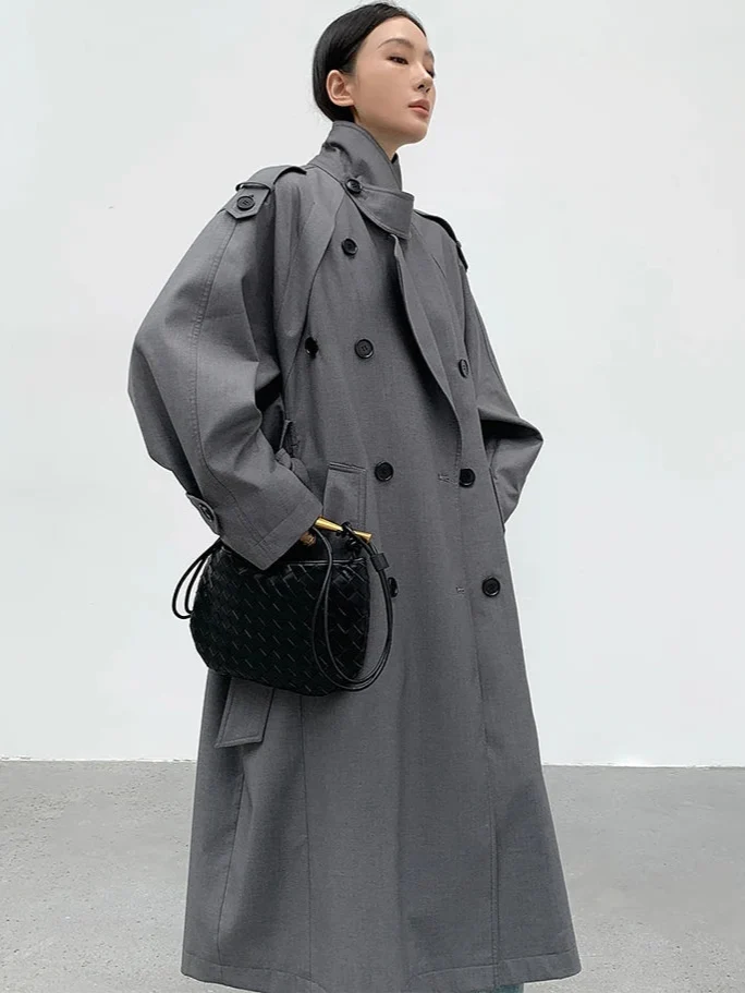 Model wearing a women's oversized long gray trench coat, showcasing its elegant drape & classic style as winter outerwear.