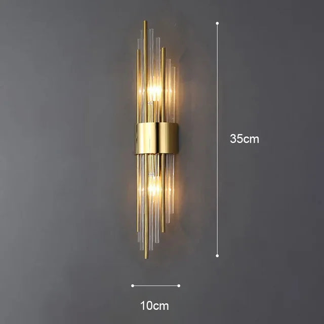 A pair of elegant gold finish LED wall sconces illuminating a modern hallway. Crystal glass detail.