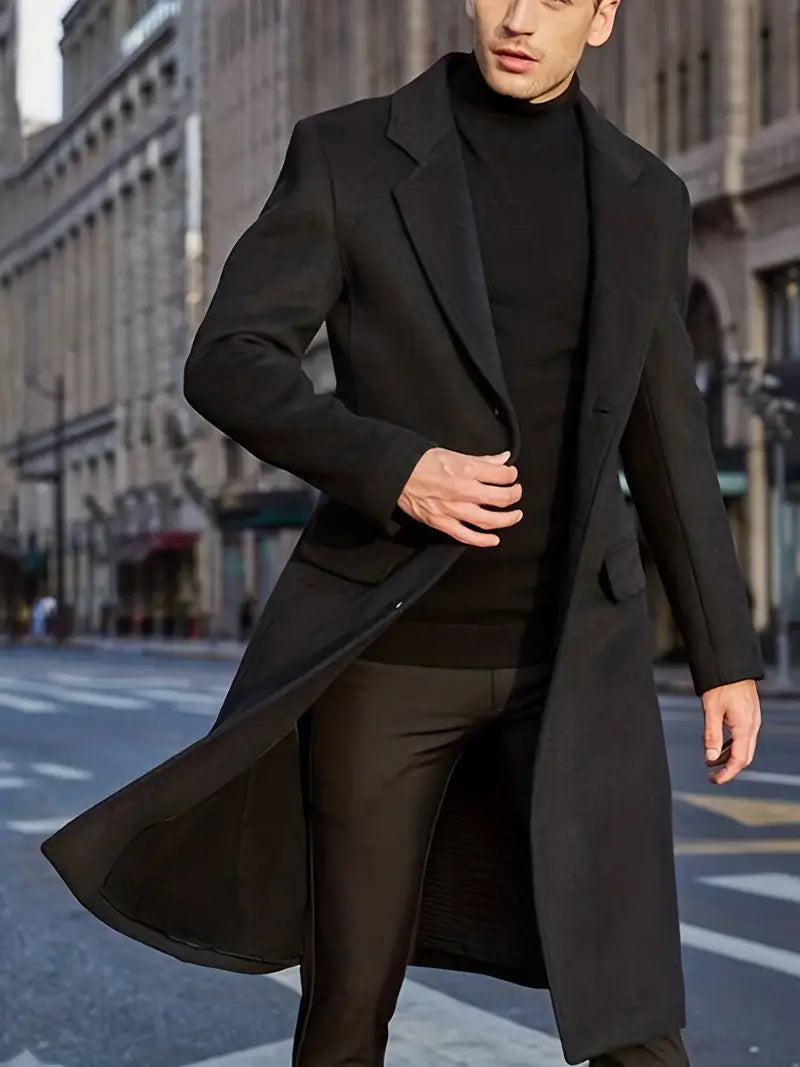 Man wearing a sleek slim fit long trench coat. This notched lapel men's outerwear is perfect for winter style.