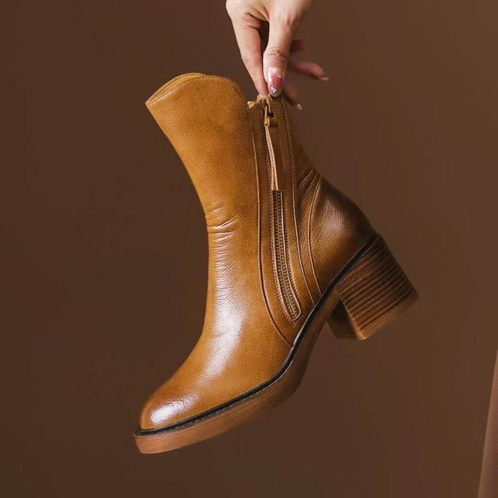 Close-up of elegant women's leather block heel ankle boot. Showcases comfortable heel & secure side zipper.