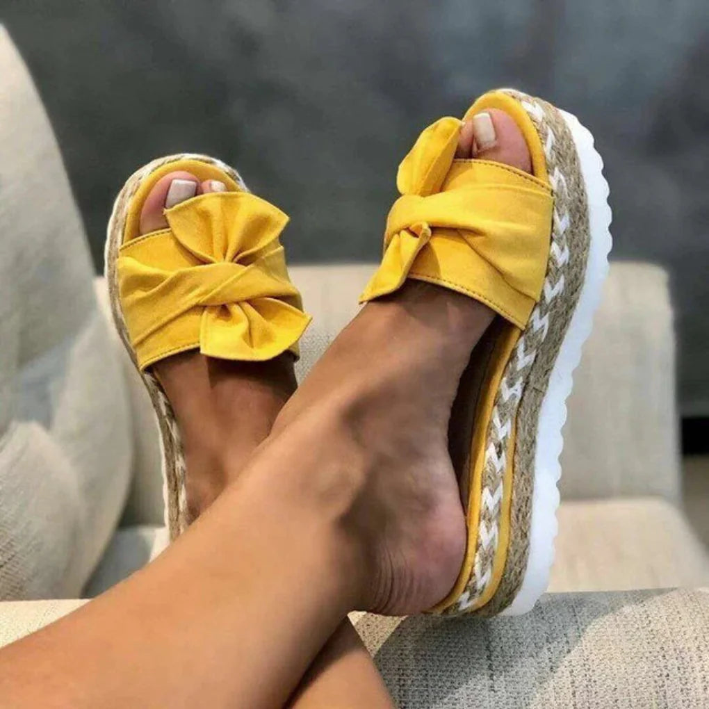 Chic women's flat slip-on sandals featuring an elegant bow detail. Perfect comfortable footwear for spring.