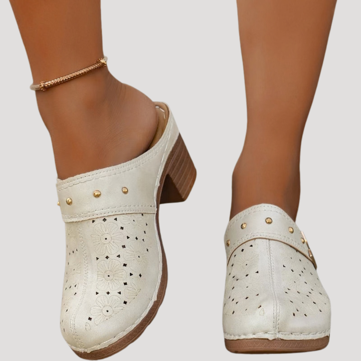 Vintage-style women's embossed clog mules with sturdy block heel and decorative buckle accent.