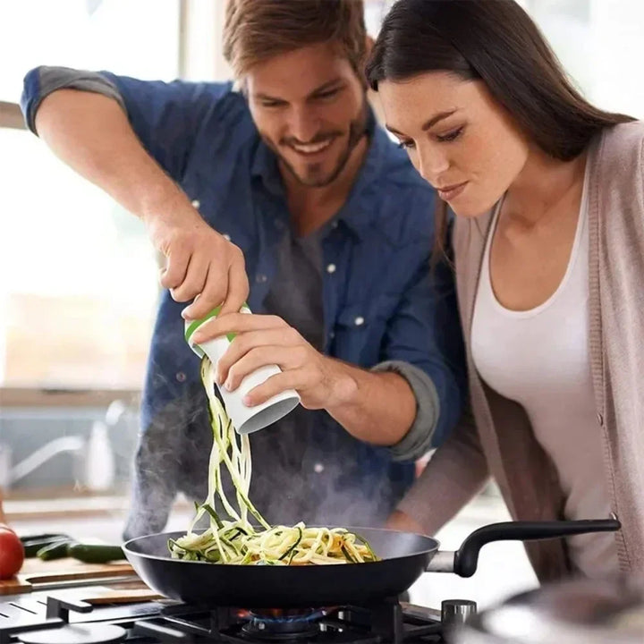Hand using a manual vegetable spiralizer to create fresh zucchini noodles. Ideal compact kitchen tool for healthy eating.