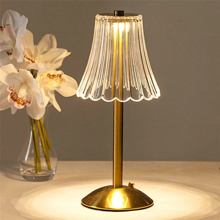 Close-up of elegant LED crystal table lamp, showing textured gold base and touch sensor.