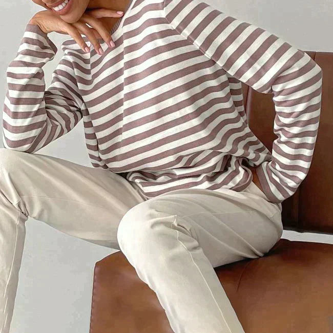 Model in a stylish women's striped knit sweater. Relaxed fit long sleeve crew neck pullover for versatile casual wear.