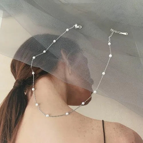 Gold triple layer necklace for women with delicate heart pendant. Features pearls and layered chains.