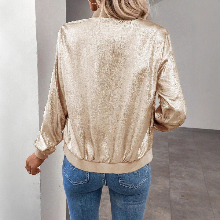 Close-up of a women's amber shiny bomber jacket, highlighting its unique fabric and functional pockets.