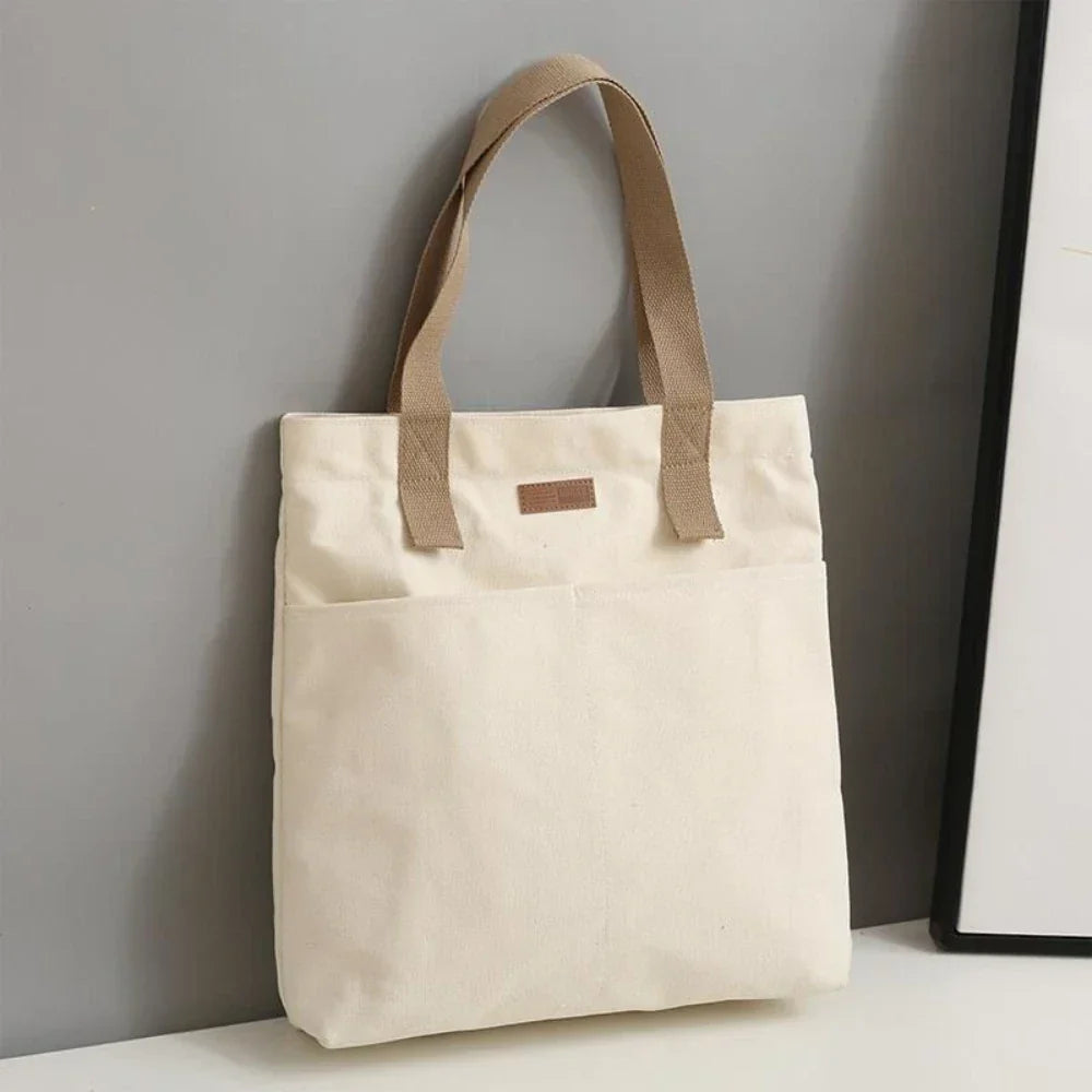 Stylish women's canvas shoulder bag, a durable beach tote with handy front pockets for a chic summer look.