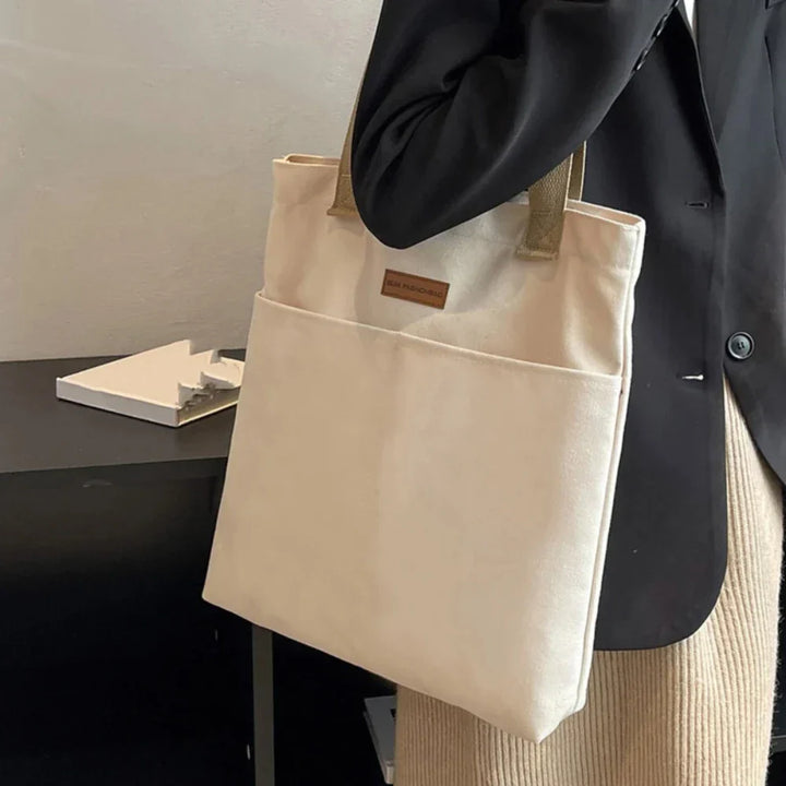Versatile women's canvas tote, ideal as a beach bag, travel bag, or everyday shoulder bag with front pockets.