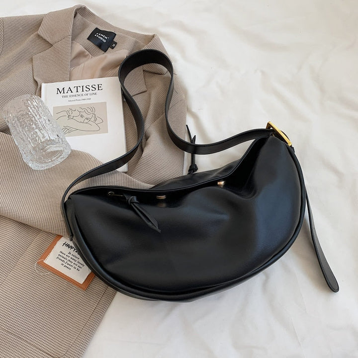 Women's minimalist half-moon crossbody bag with adjustable strap, perfect for versatile everyday use.