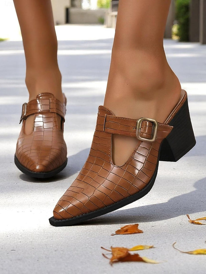 Elegant slip-on women's mules featuring a stylish cut-out design and buckle detail. Versatile block heel shoe.
