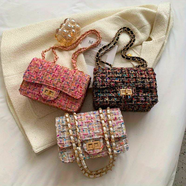 Close-up of elegant women's structured bouclé shoulder bag, highlighting the textured fabric and chic chain detail.