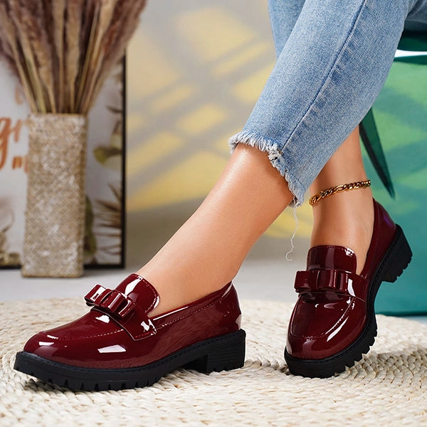 Women's slip-on platform loafers in black, featuring an elegant bow and durable lug sole.
