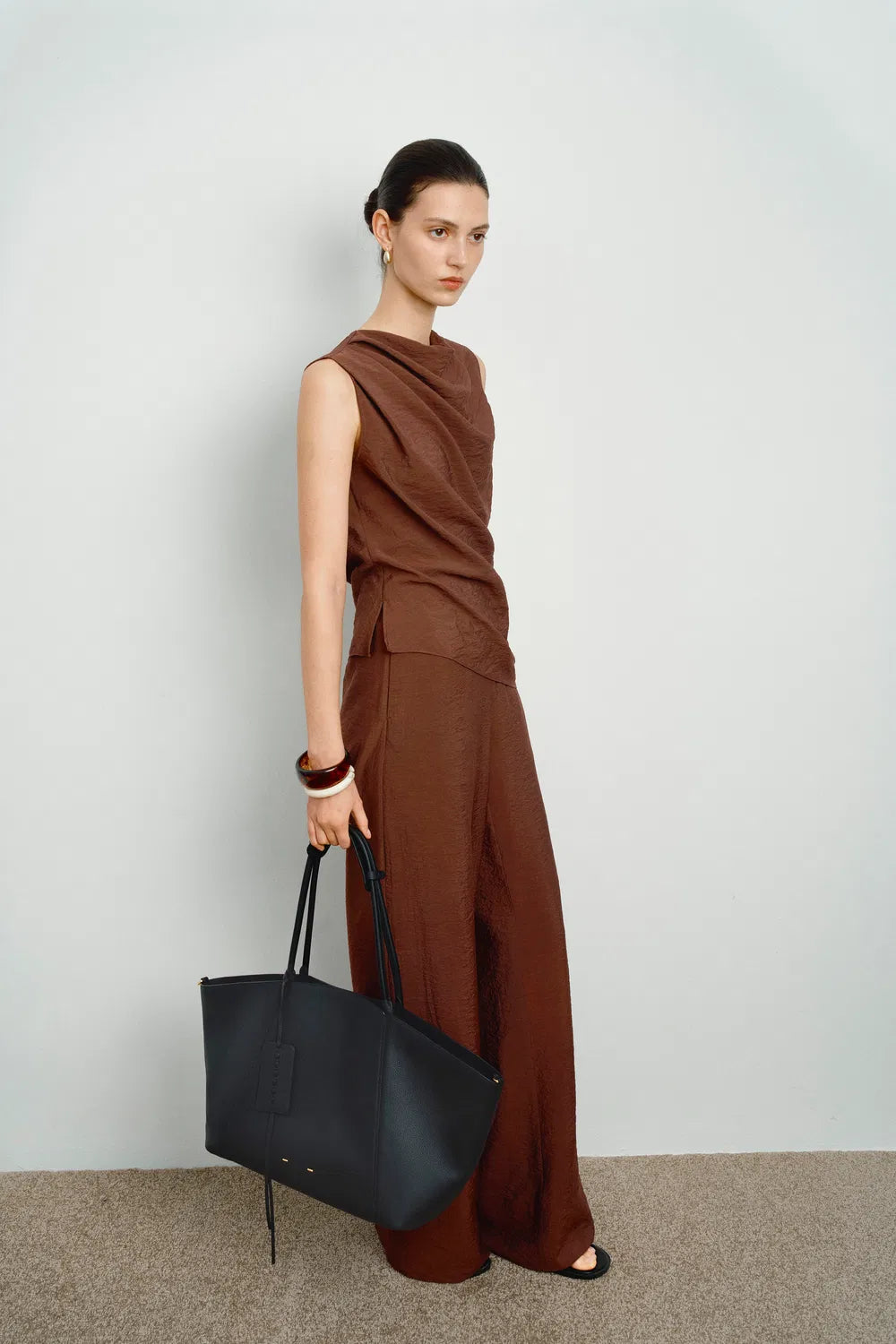 Woman holding a stylish brown spacious everyday travel tote bag, ideal for modern fashion.