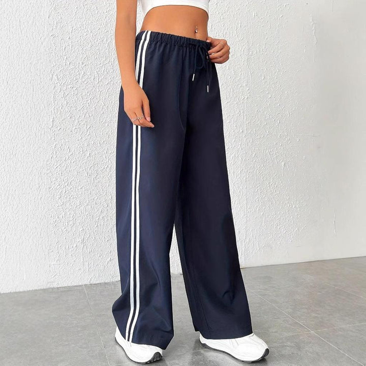 Comfortable women's dark blue wide leg track pants featuring a white side stripe & elastic waist. Loungewear.