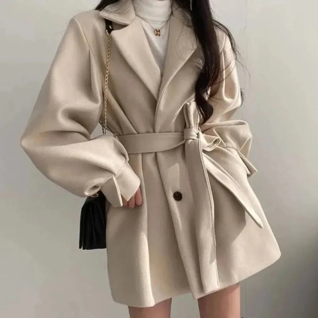 Black women's oversized trench coat, featuring wide lapel, belt & chic puff sleeves. Smart casual outerwear.